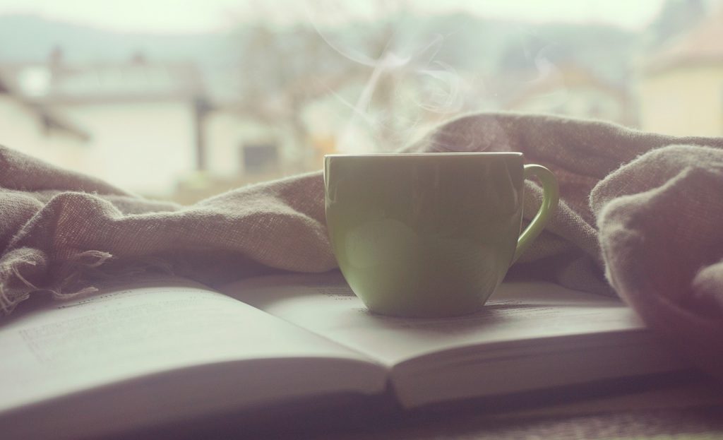 Tasse de café posée sur un livre au bord d'une fenêtre