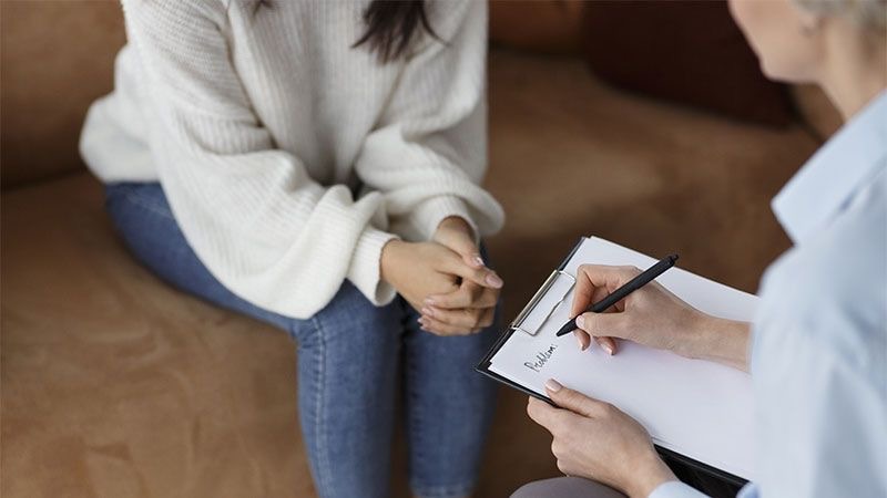 Un thérapeute en consultation avec une femme. Le thérapeute prenant des notes.