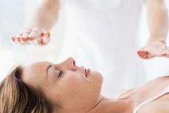 Une personne réalisant un soin énergétique sur une femme